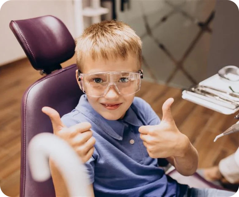 Happy child at dentist giving thumbs up