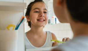 Young girl from Oakland looking her self in the mirror, and brushing her teeth